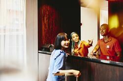 Man and woman working at a hotel reception desk helping a guest.