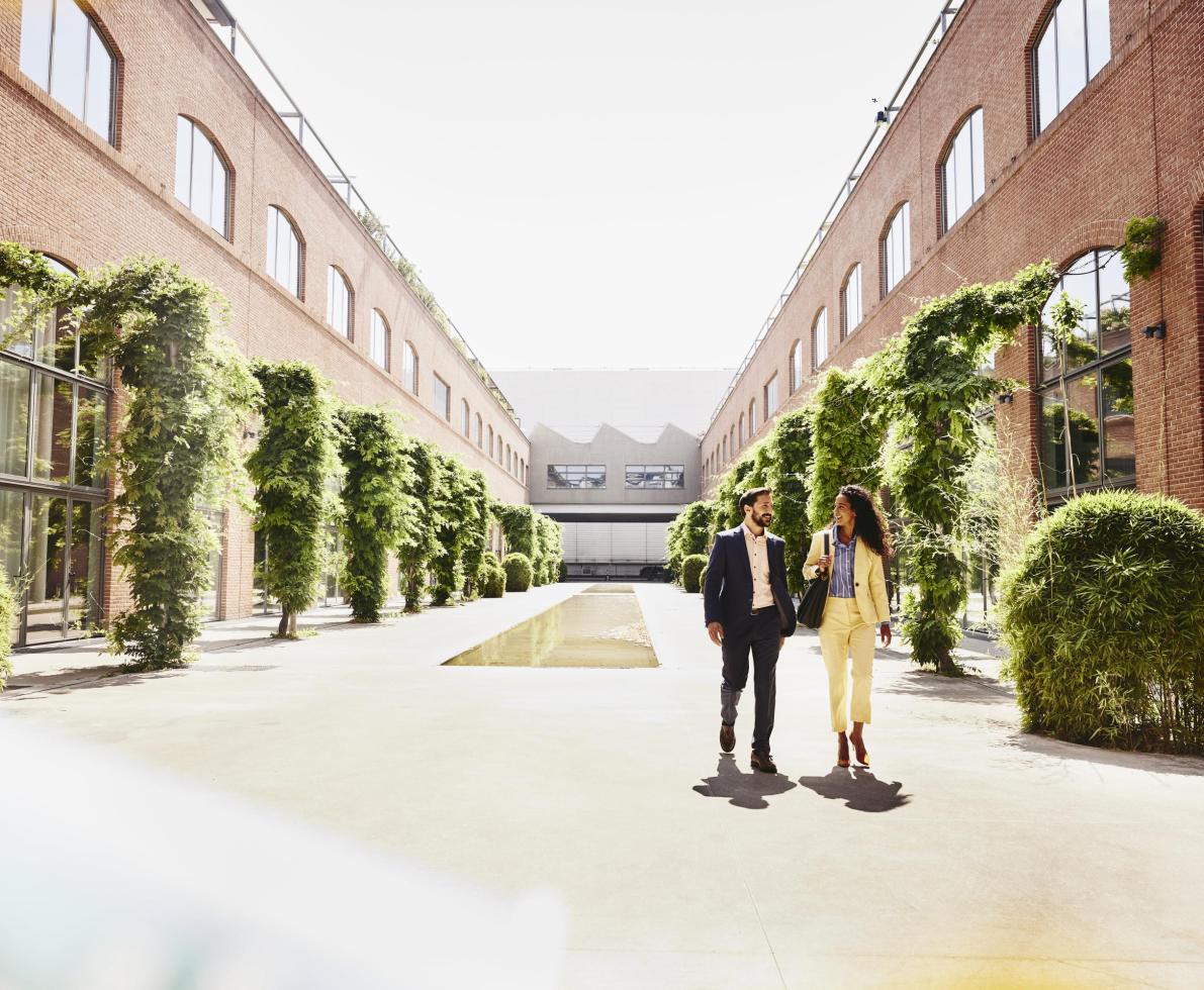 Man and woman walking outside between office buildings.