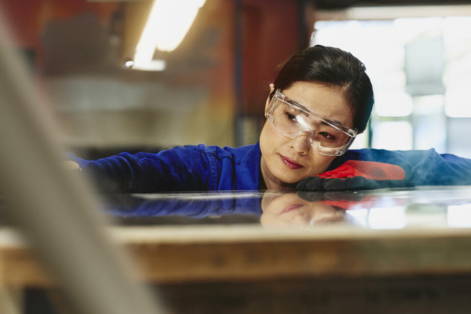 Womale wearing safety glasses and gloves watching a process closely.
